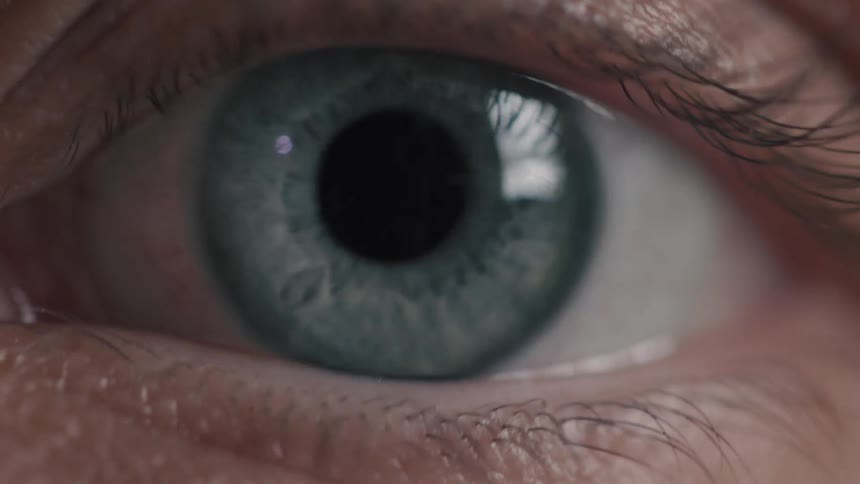 An intense macro shot of a blue human eye looking around and then slowly closing