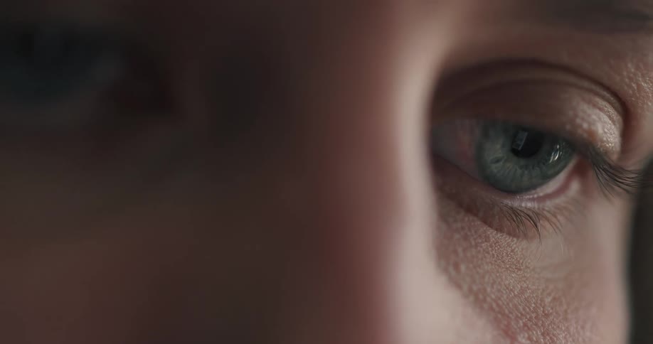 A captivating macro shot shows a human eye focused intently, with the light and information from a digital screen reflected in the pupil
