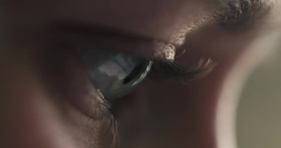 An extreme close-up side view of a human eye as it reflects the light from a screen