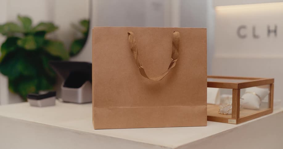A plain brown paper shopping bag sits on a white counter in a modern retail boutique