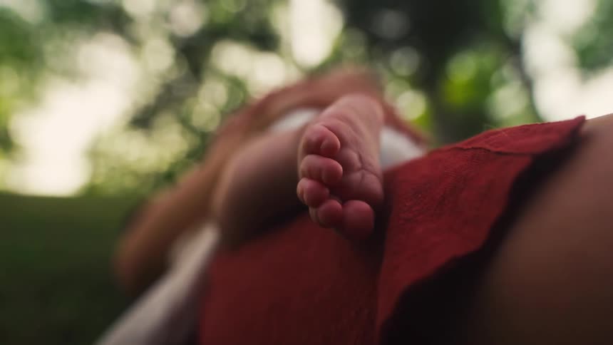 Close-up on a newborn baby's tiny foot resting peacefully outdoors with soft, natural lighting
