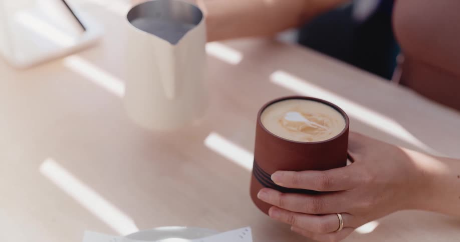 A close-up slow motion shot of pouring frothed milk into a coffee cup to create latte art