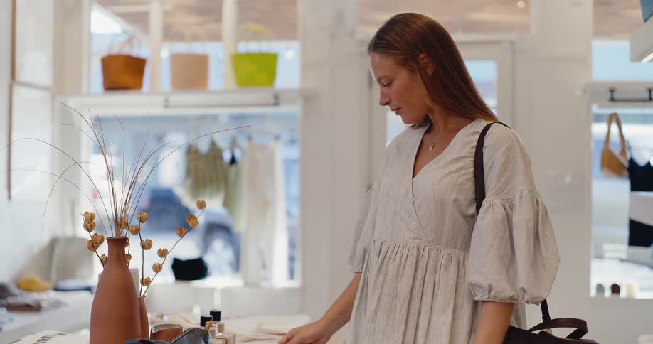 A stylish young woman smiles as she browses merchandise in a bright and airy boutique