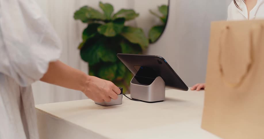 A woman inserts her credit card into a point of sale terminal to pay for her purchase at a retail store