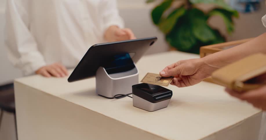 A customer uses a credit card to make a contactless payment at a modern retail store's point-of-sale terminal