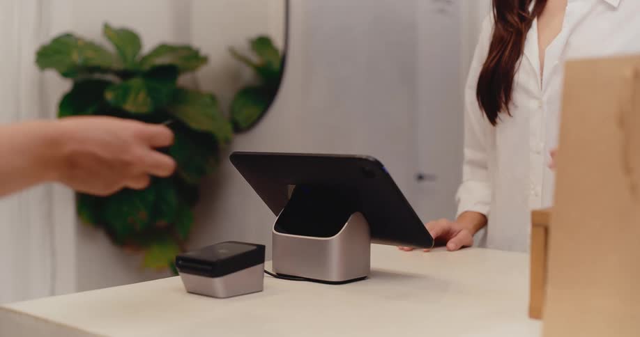A customer completes a purchase in a modern retail store by swiping their credit card at the checkout counter