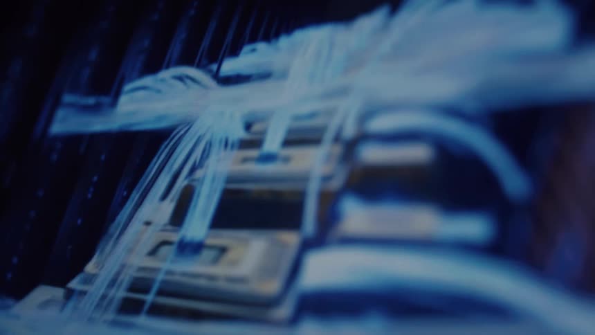 Futuristic blue-lit computer server with glowing fiber optic cables transferring data through microchips in a slow dolly shot