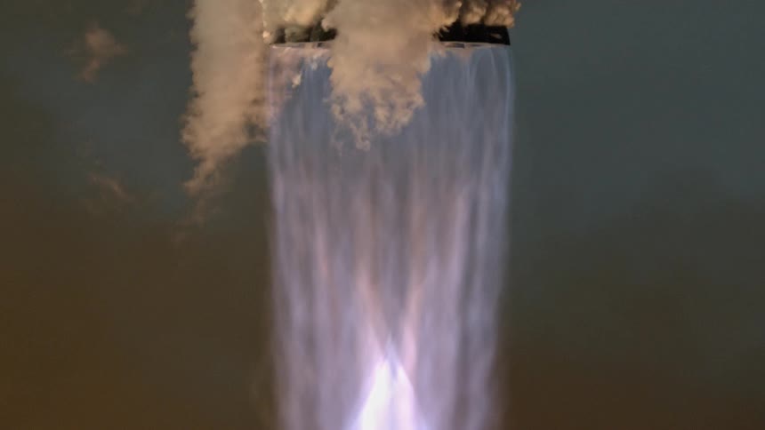 A dramatic close-up of a powerful rocket engine spewing blue flames and thick white smoke