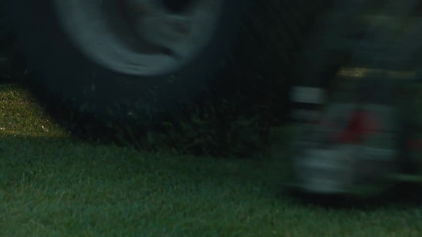 A close-up shot of a ride-on lawn mower cutting the lush green grass on a golf course