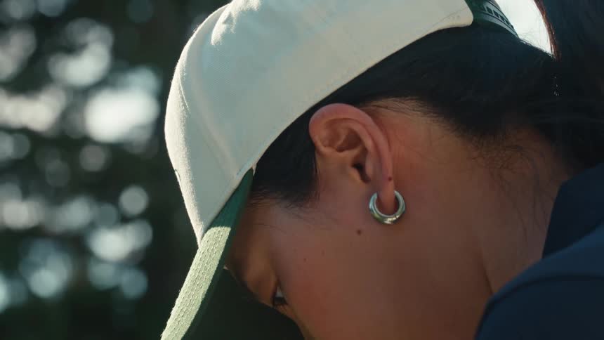 A close-up slow-motion shot of a thoughtful woman in a baseball cap looking up with focus
