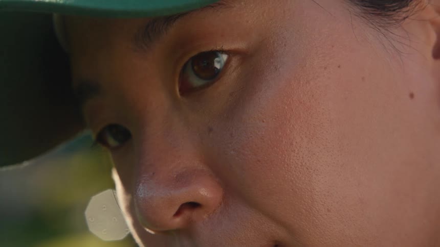 An intimate close-up of a young Asian woman's face as she looks up with a pensive expression