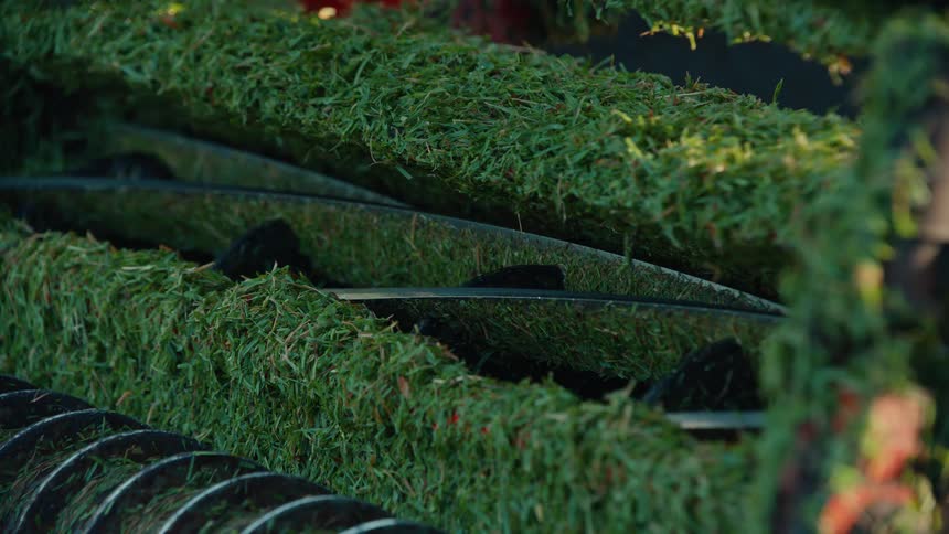Macro view of stationary lawnmower blades covered in fresh green grass clippings