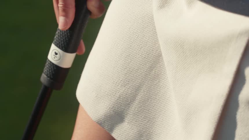 A close-up slow-motion shot of a woman's hands adjusting her grip on a golf club handle on a sunny day