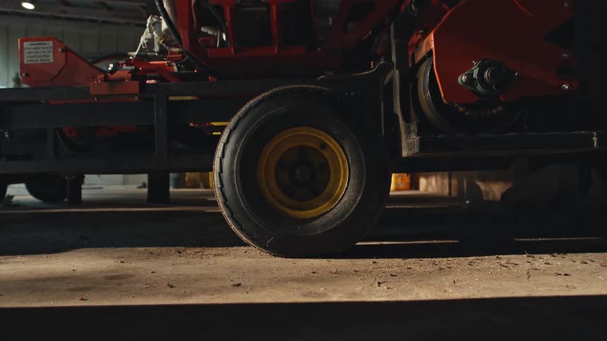 Timelapse of shadows moving across a wheel on a piece of farm equipment parked inside a barn