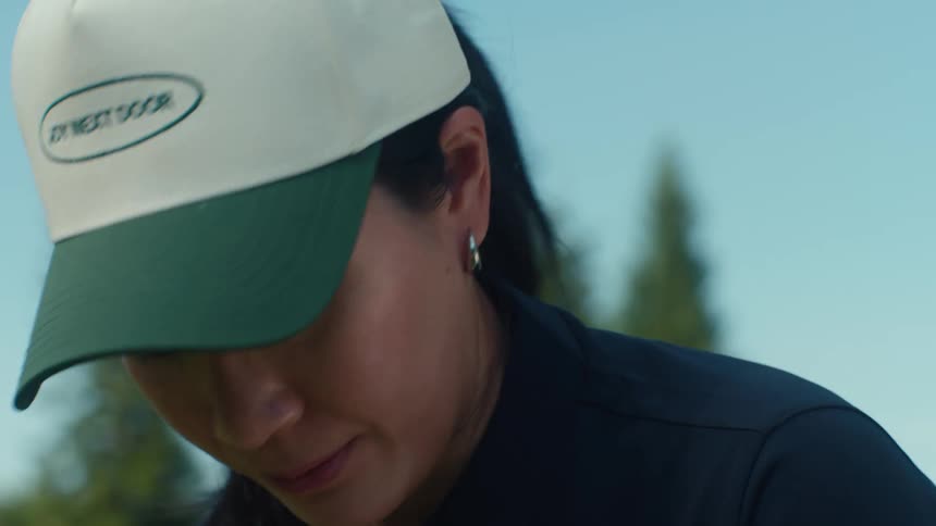 Close-up of a focused Asian woman wearing a baseball cap concentrating on her next move on a sunny day