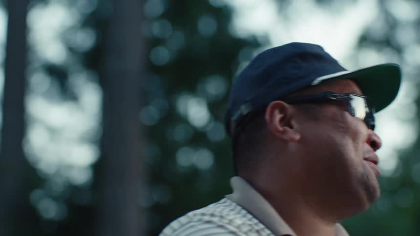 A man in a cap and sunglasses reacts with a shout and a smile in slow motion