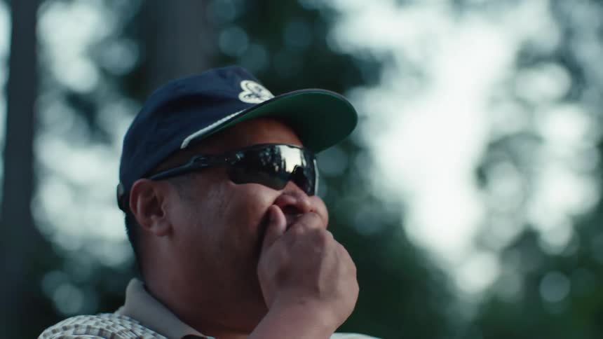 Candid shot of a man wearing sunglasses reacting with laughter to a smell while outdoors