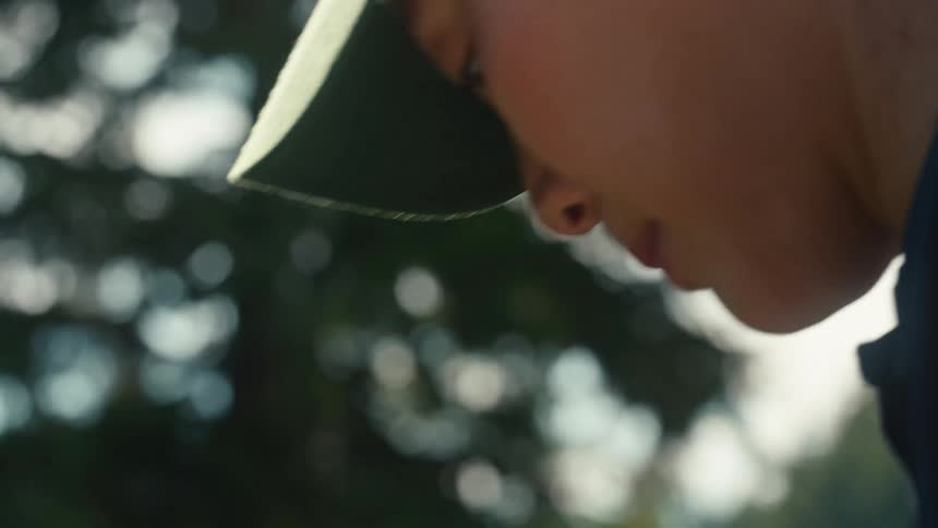 Close-up slow motion shot of a focused woman in a baseball cap looking up with determination