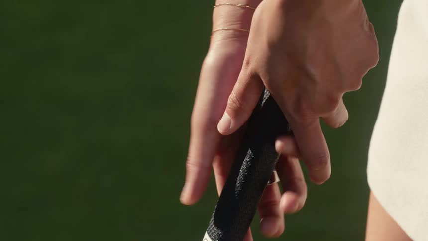 Close-up slow motion shot of a woman's hands gripping and adjusting a golf club before taking a swing