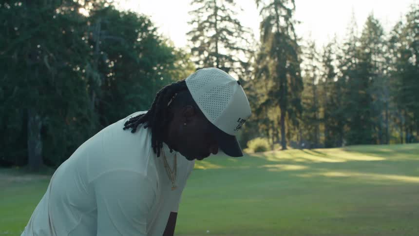 Slow motion close-up of a stylish man with dreadlocks swinging a golf club on a beautiful course