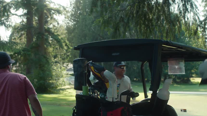A group of friends gets ready for a round of golf, grabbing their clubs from the cart on a sunny day
