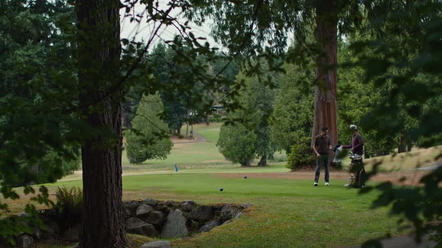 A group of men walk onto a scenic, tree-lined golf course and get ready to tee off for a relaxing game