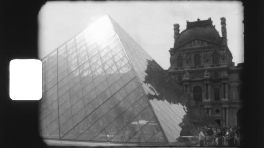 Vintage black and white 8mm film captures a slow pan of the iconic glass pyramid at the Louvre Museum in Paris, France