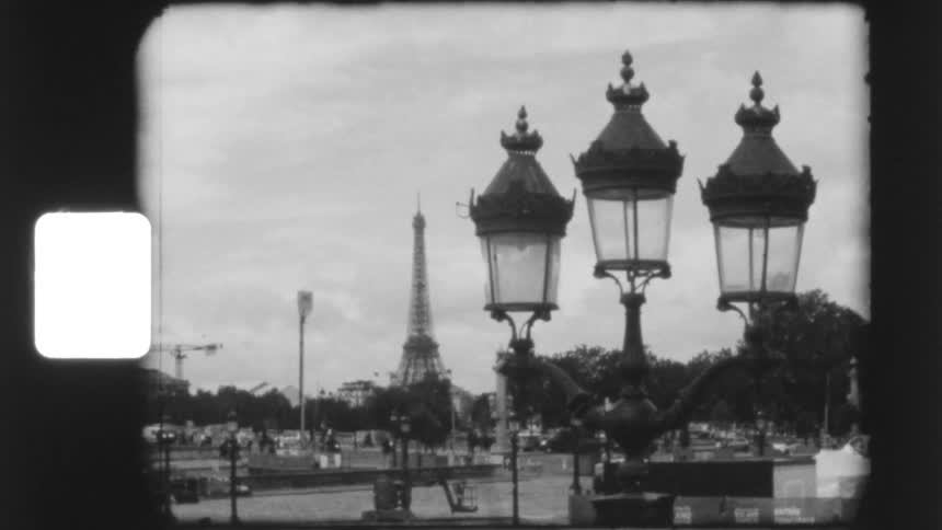 Vintage black and white 8mm film captures a classic view of the Eiffel Tower behind an ornate Parisian street lamp
