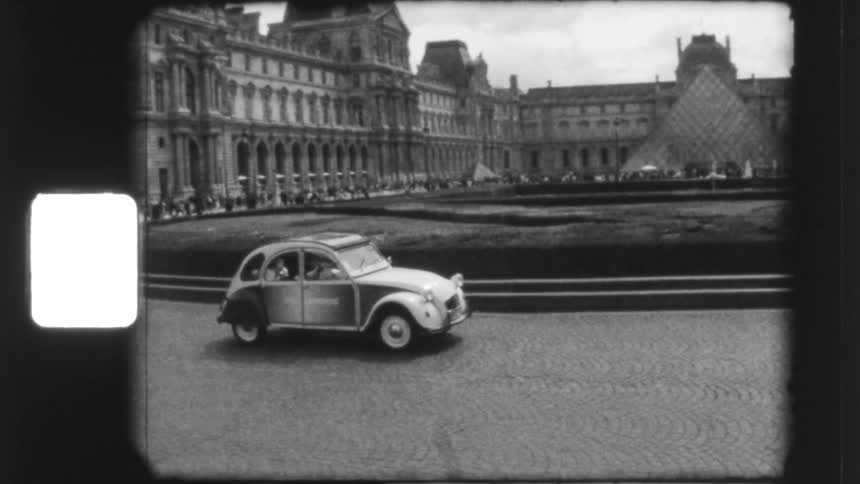 A classic Citroën 2CV car drives past the iconic Louvre Museum in this authentic black and white vintage footage from Paris