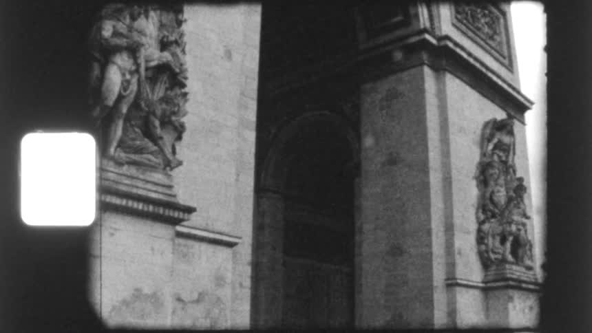 Vintage 8mm black and white footage captures the detailed sculptures on the famous Arc de Triomphe in Paris
