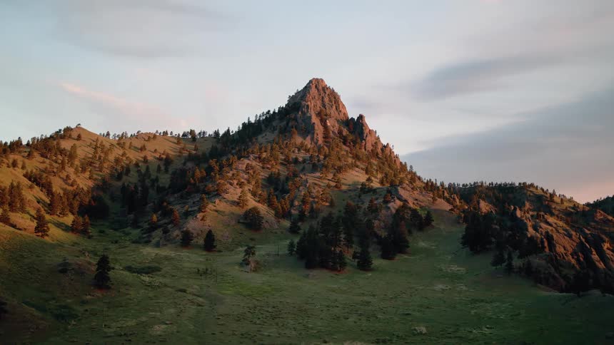 A majestic mountain peak is illuminated by the golden light of sunset as the camera slowly pushes in