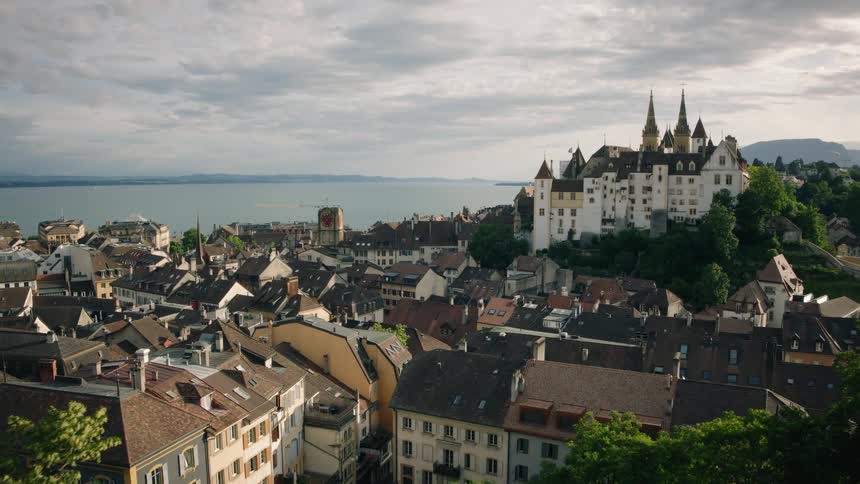 A slow aerial reveal of the magnificent Château de Neuchâtel overlooking the old town and tranquil lake in Switzerland