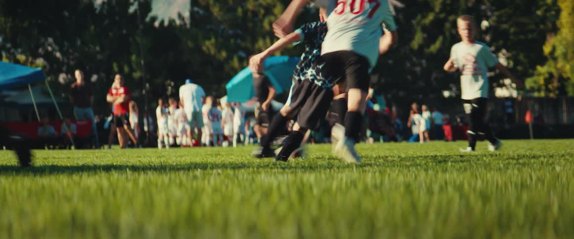 A dynamic low-angle view captures young boys competing in a fast-paced soccer game on a sunny field