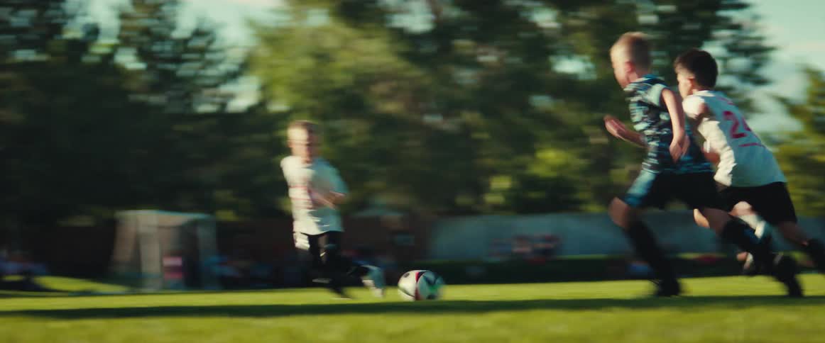 Energetic young boys chase a soccer ball down the field during a competitive game