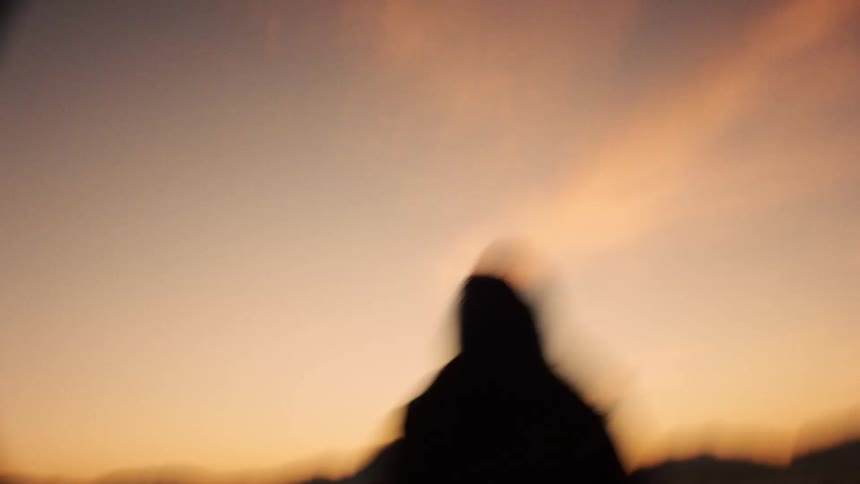 A shaky, dreamy handheld shot follows a smiling woman as she walks through the beautiful white sand dunes at sunset