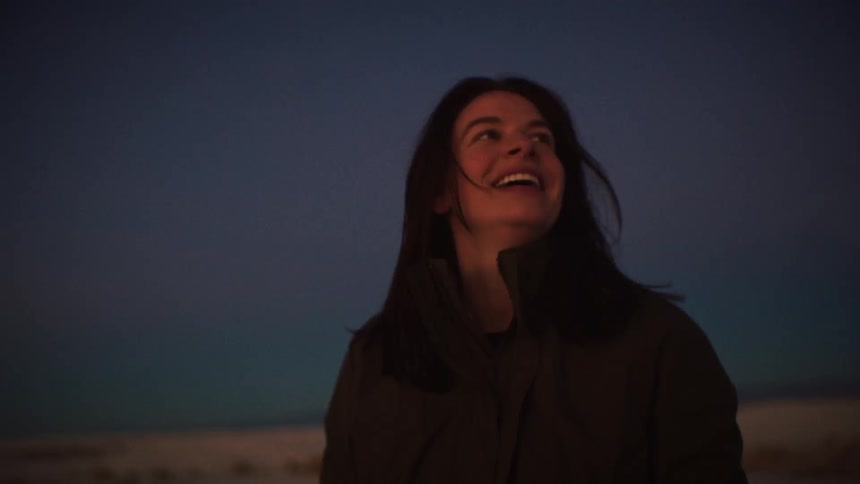 A woman's face lights up with wonder and joy as she gazes up at the beautiful twilight sky