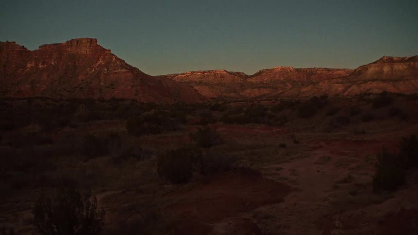 A beautiful timelapse shows the sun rising over a vast red rock canyon, slowly illuminating the desert landscape
