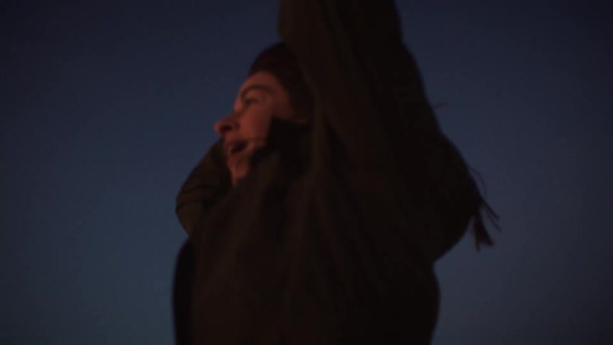 A woman filled with pure joy laughs ecstatically towards the dark evening sky in a beautiful slow-motion shot