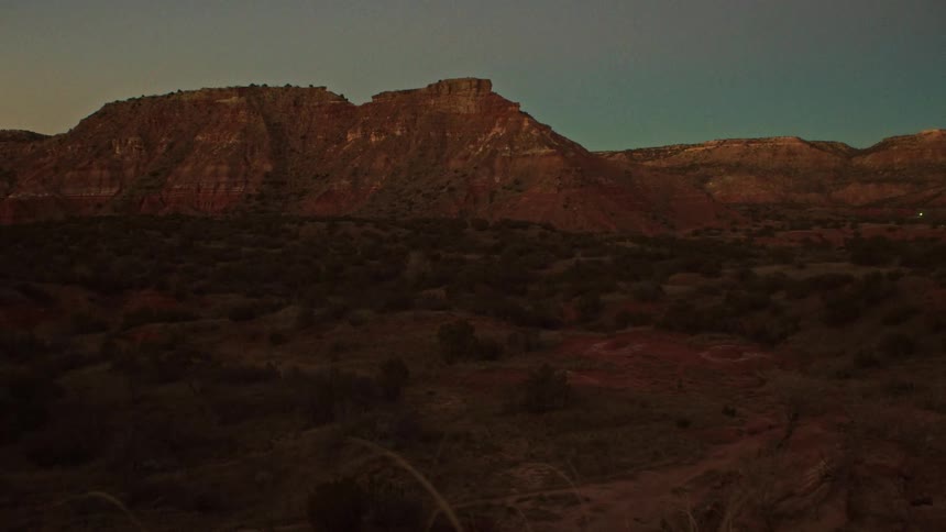 A tranquil wide shot of a red rock canyon landscape settles into a slow pan under the fading light of dusk