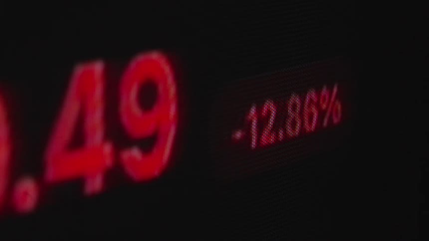 A close-up of a volatile stock or cryptocurrency price fluctuating rapidly between green gains and red losses on a digital screen