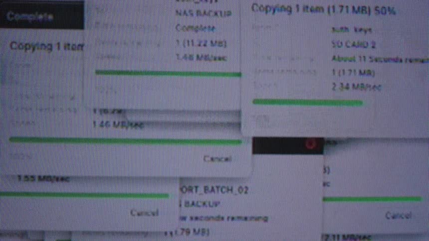 A chaotic close-up of a computer screen shows multiple glitchy file transfer windows with green progress bars