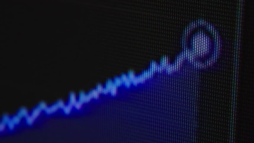 Macro view of a blue line graph charting upward growth on a dark digital screen