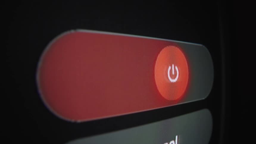 Close-up of smartphone screen sliding the red power off button across a dark interface
