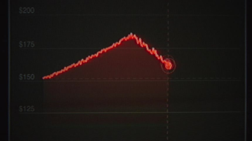 A financial graph on a screen shows a rising stock price that peaks and then suddenly crashes
