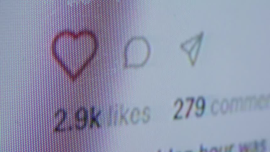 A close-up macro shot of a social media post on a screen showing the number of likes and comments rapidly increasing as it goes viral