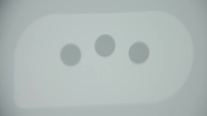 An out-of-focus close-up of a pulsating three-dot ellipsis icon on a screen, indicating someone is typing a message