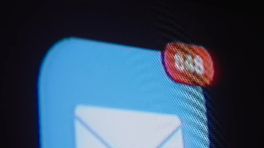 Macro shot of an email app icon on a screen as the unread message notifications rapidly increase into the hundreds