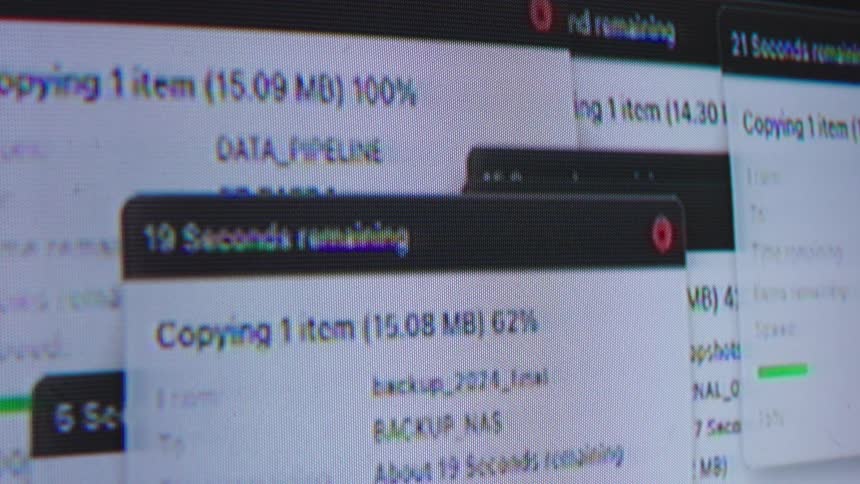 A close-up view of a computer screen shows multiple overlapping windows with data files being copied and transferred, suggesting hacking or a large data backup