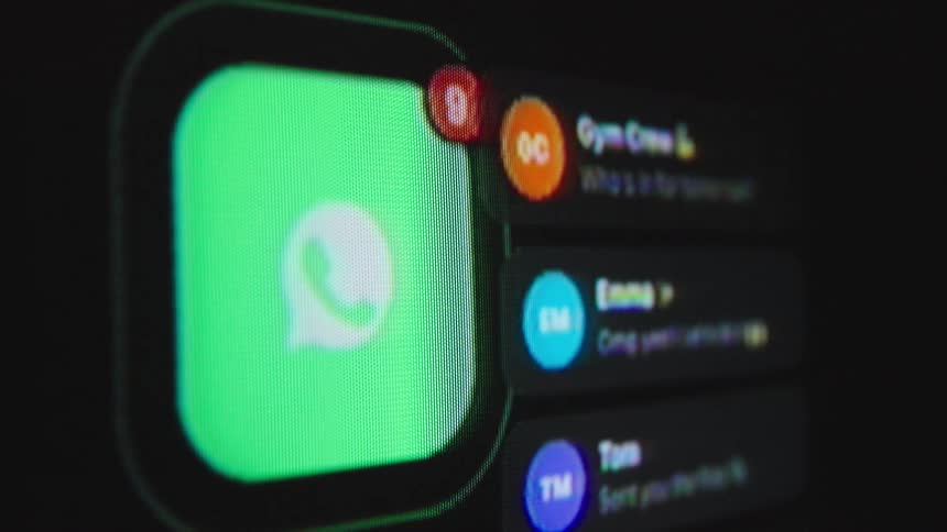 A close-up macro shot of a screen showing the WhatsApp icon as message notifications rapidly increase, symbolizing constant digital communication
