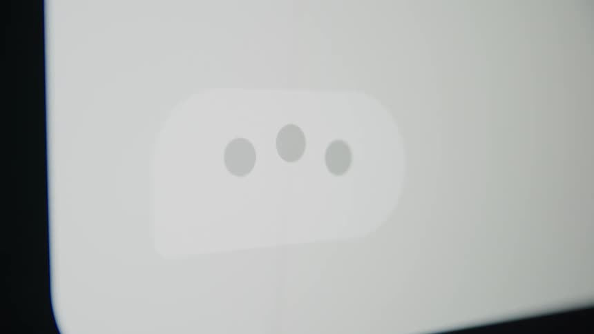 A close-up macro shot of a messaging app's typing indicator with three pulsing dots on a screen